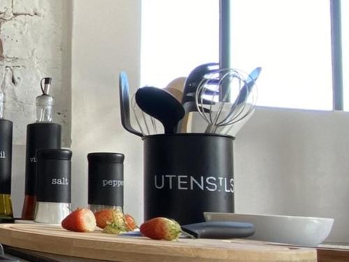 a black container with utensils on a cutting board at Bellamore - Stylish Loft Studio with Sea Views in Brenton-on-Sea