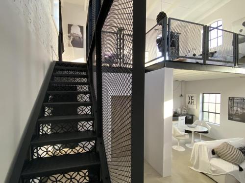 a black spiral staircase in a room with a living room at Bellamore - Stylish Loft Studio with Sea Views in Brenton-on-Sea