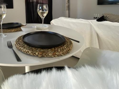 a table with a black plate and glasses of wine at Bellamore - Stylish Loft Studio with Sea Views in Brenton-on-Sea