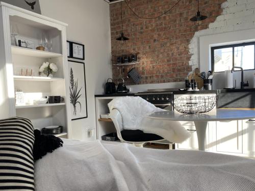a kitchen with a table and a brick wall at Bellamore - Stylish Loft Studio with Sea Views in Brenton-on-Sea