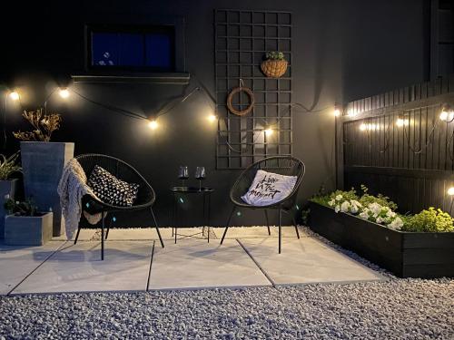 two chairs and a table in a patio with lights at Bellamore - Stylish Loft Studio with Sea Views in Brenton-on-Sea