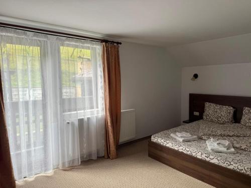 a bedroom with a bed and a large window at Casa din Codru in Şimon