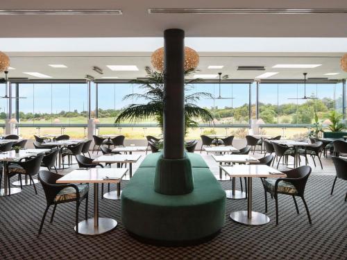 a restaurant with tables and chairs and a fireplace at Pullman Magenta Shores Resort in The Entrance