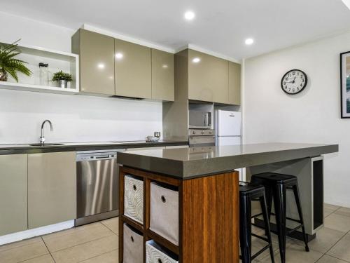 an empty kitchen with a counter and a clock on the wall at Pullman Magenta Shores Resort in The Entrance