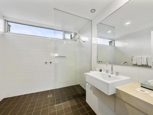 a white bathroom with a sink and a mirror at Pullman Magenta Shores Resort in The Entrance