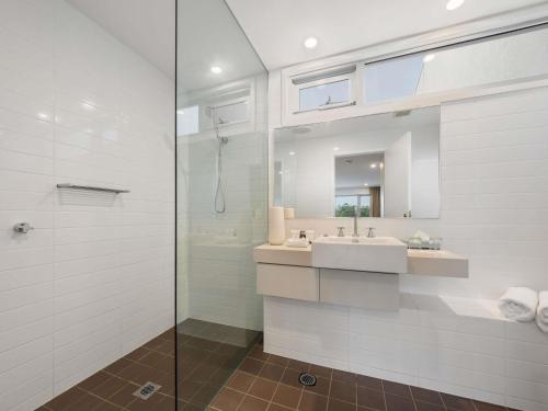 a bathroom with a sink and a glass shower at Pullman Magenta Shores Resort in The Entrance