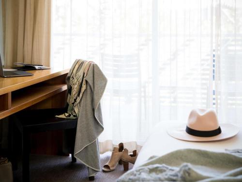 a hat sitting on a desk next to a bed at Pullman Magenta Shores Resort in The Entrance
