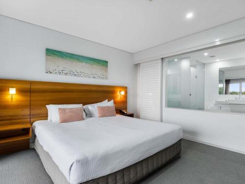 a bedroom with a large bed and a sink at Pullman Magenta Shores Resort in The Entrance