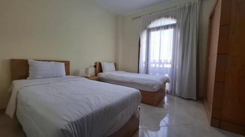 a hotel room with two beds and a window at SHL Hurghada Hotel Apartments Sahl Hasheesh - By SAHLHOMES in Hurghada