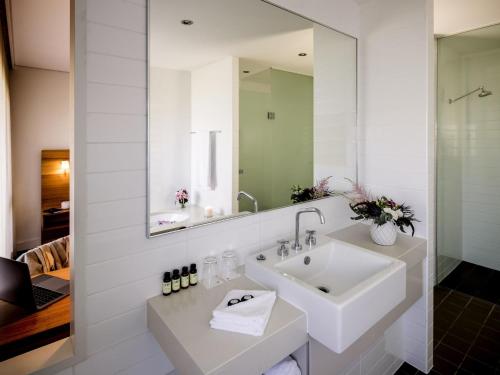 a bathroom with a sink and a mirror at Pullman Magenta Shores Resort in The Entrance