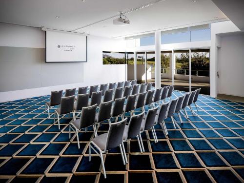 a conference room with chairs and a screen in it at Pullman Magenta Shores Resort in The Entrance