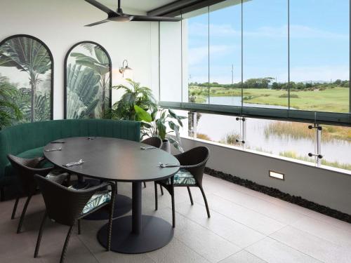 a dining room with a table and chairs and windows at Pullman Magenta Shores Resort in The Entrance