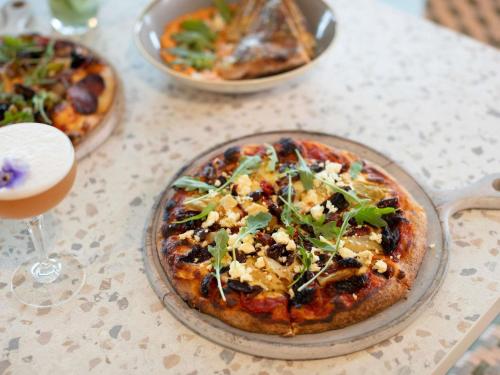 a table with two pizzas and a glass of wine at Pullman Magenta Shores Resort in The Entrance