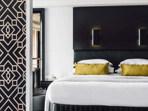 a bedroom with a large white bed with yellow pillows at The Como Melbourne in Melbourne