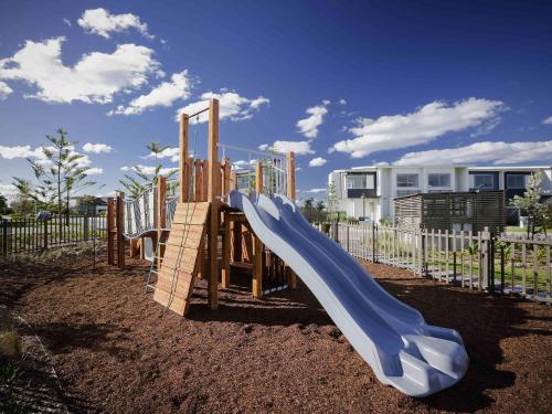 a playground with a slide in a yard at Pullman Magenta Shores Resort in The Entrance