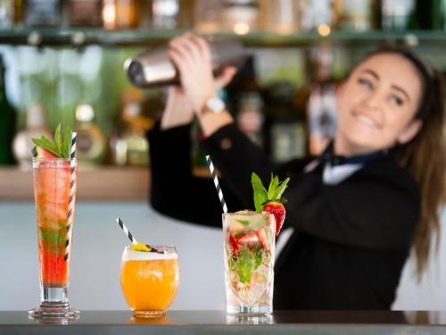 a woman sitting at a table with two cocktails at Pullman Magenta Shores Resort in The Entrance
