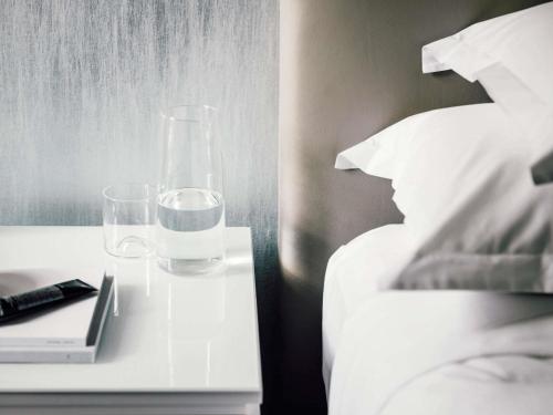 a bed with a table with two glasses and a book at The Como Melbourne in Melbourne