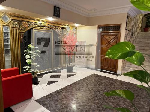 a lobby with a red chair and a door at Hotel Seven 7 in Karachi