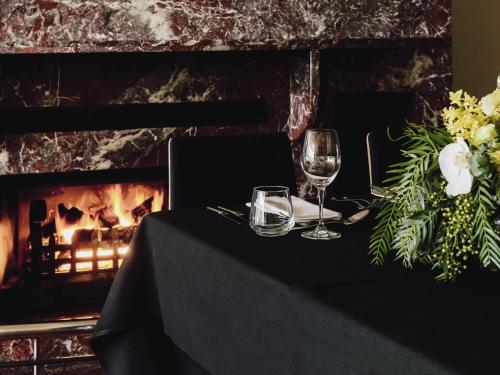 a table with two wine glasses and a fireplace at The Como Melbourne in Melbourne