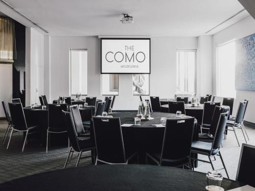 a conference room with tables and chairs and a screen at The Como Melbourne in Melbourne