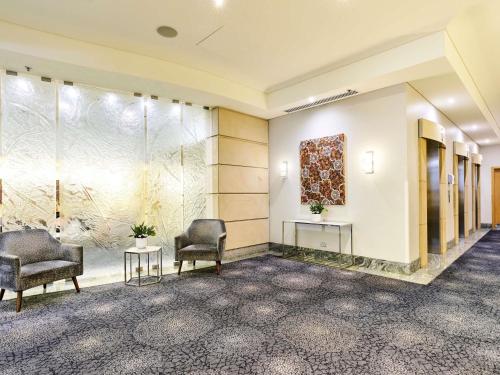 a lobby with two chairs and a painting on the wall at The Sebel Sydney Chatswood in Sydney