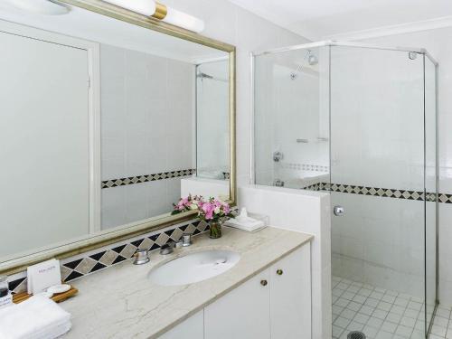 a white bathroom with a sink and a mirror at The Sebel Sydney Chatswood in Sydney
