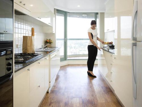 a woman standing in a kitchen preparing food at The Sebel Sydney Chatswood in Sydney