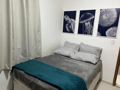 a bed in a room with three pictures on the wall at Apto Pé na Areia, Vila Caiçara in Praia Grande