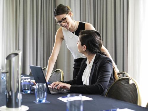 two women sitting at a table with a laptop at The Sebel Sydney Chatswood in Sydney