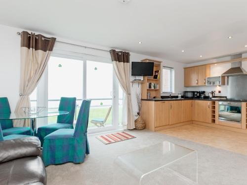 a living room with a glass table and blue chairs at Beachlands in Llanelli