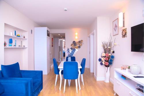 a living room with a dining room table and blue chairs at Astounding Sea View Aparthotel In Orbi City Batumi in Batumi