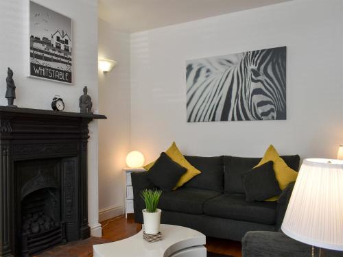 a living room with a couch and a fireplace at Shingle Cottage in Whitstable