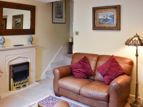 a brown leather couch in a living room with a fireplace at Eden Cottage in Cerne Abbas