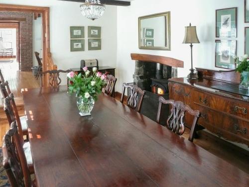 Un comedor con una mesa con un jarrón de flores. en Dove Cote House, en Westleigh