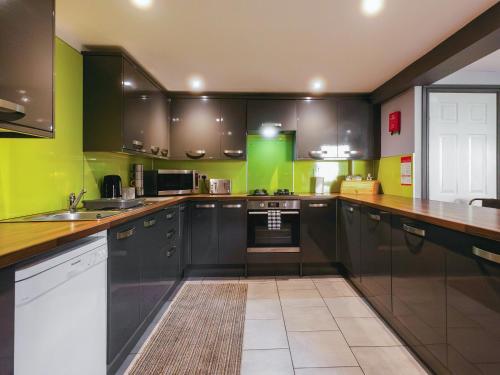 a kitchen with black cabinets and green walls at St Hildas Rest in Hinderwell