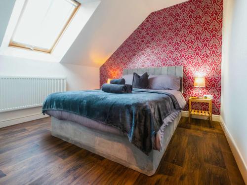 a bedroom with a large bed with a red wall at St Hildas Rest in Hinderwell