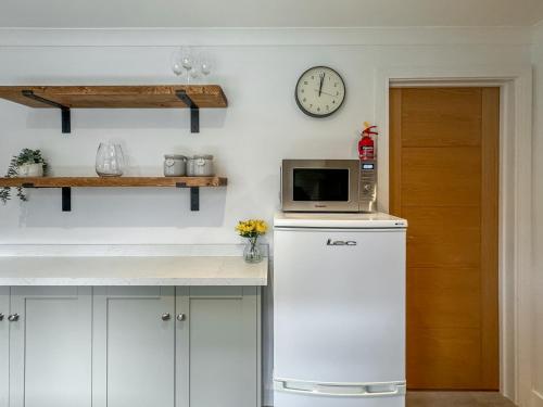cocina con microondas y reloj en la pared en Lower Moon, en Port Isaac