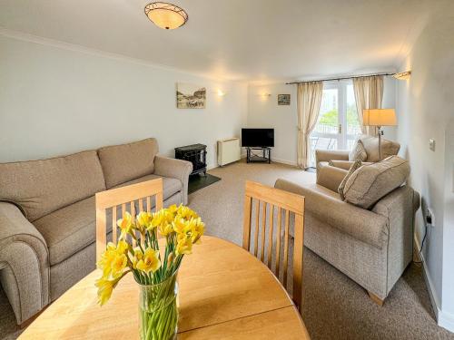 a living room with a couch and a table with flowers on it at Lower Moon in Port Isaac