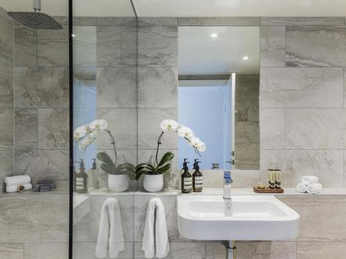 a bathroom with a sink and a mirror at Quay West Suites Melbourne in Melbourne