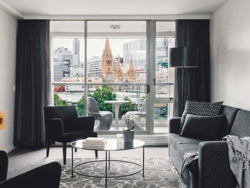 a living room with a view of a city at Quay West Suites Melbourne in Melbourne