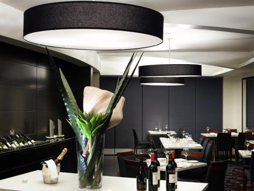 a dining room with a vase of flowers and wine bottles at Quay West Suites Melbourne in Melbourne