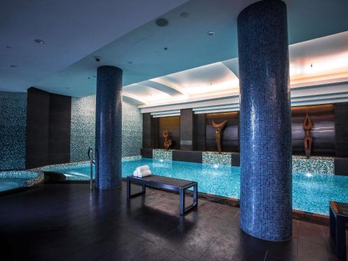 a large swimming pool in a hotel with columns at Quay West Suites Melbourne in Melbourne