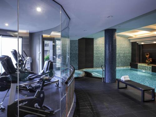 a fitness room with a swimming pool and a gym at Quay West Suites Melbourne in Melbourne