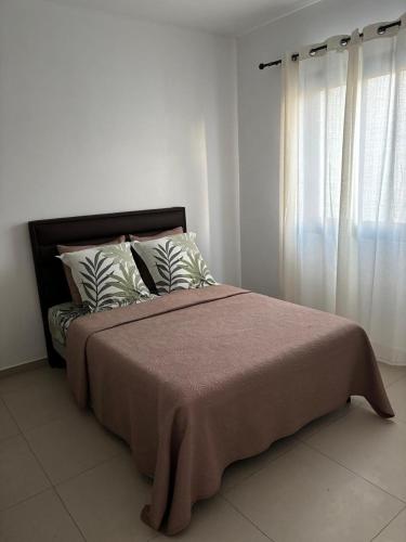 a bed in a white room with a window at Le meublé du Sable Nwar in Étang-Salé