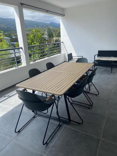 a wooden table and chairs on a balcony at Le meublé du Sable Nwar in Étang-Salé