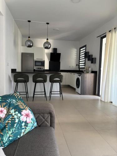 a living room with a couch and a kitchen at Le meublé du Sable Nwar in Étang-Salé