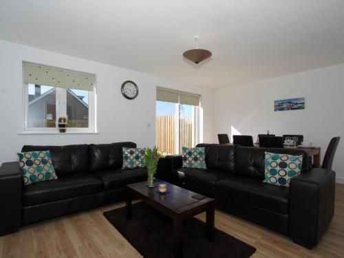 a living room with a black couch and a table at 6 Jubilee Close in St Merryn