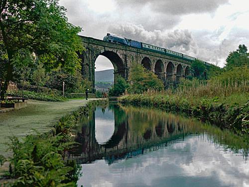 a train on a bridge over a river at The Dairy in Delph