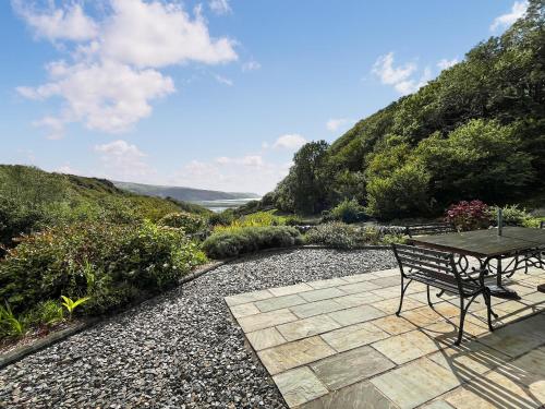 a patio with a table and a bench on a hill at Bryn Derw in Barmouth