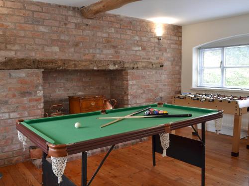 a room with a pool table and a brick wall at The Old Stables in Standon